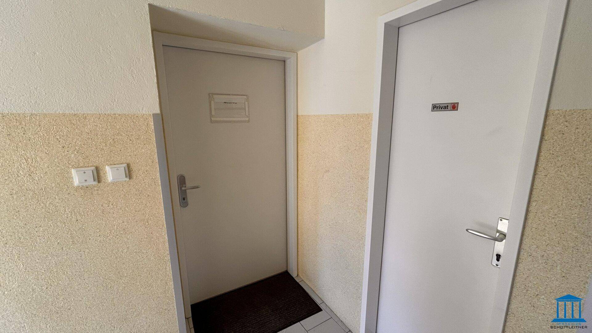 Flur mit zwei Türen und einer zweifarbigen Wandgestaltung in Beige und Weiß.