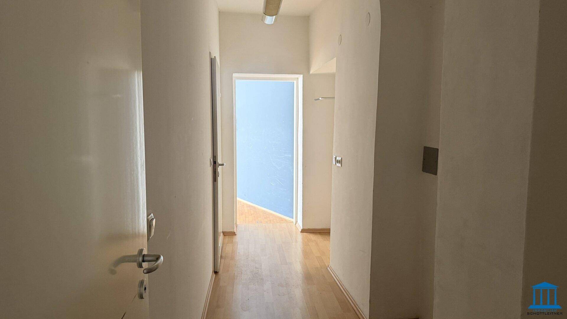 Heller Flur mit Holzboden und mehreren Türen, der verschiedene Räume miteinander verbindet.