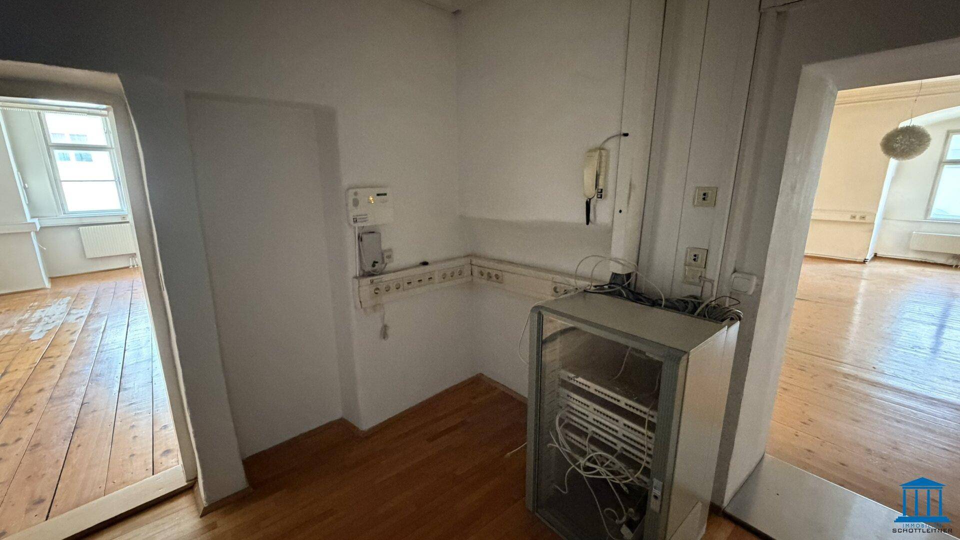 Kleiner Technikraum mit Serverrack und Verkabelung, ideal für IT-Infrastruktur.