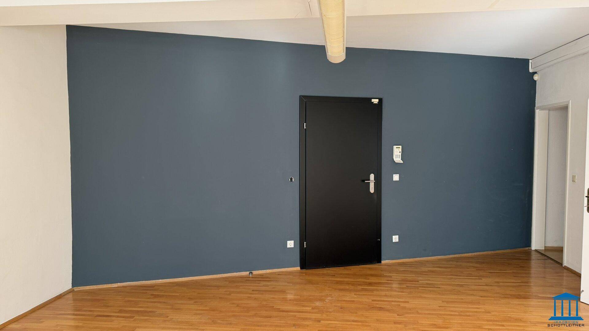 Moderner Büroraum mit einer dunkelblauen Akzentwand und Holzboden, bietet eine stilvolle Arbeitsumgebung.