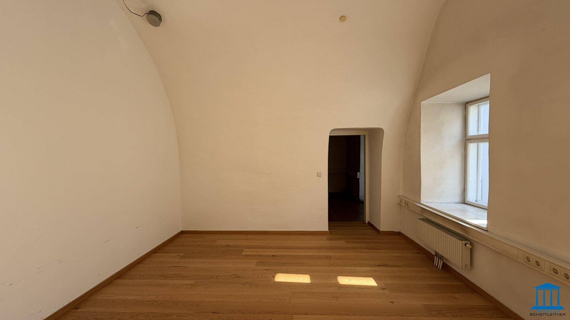 Heller Raum mit gewölbter Decke und Holzboden, bietet eine einzigartige architektonische Atmosphäre.