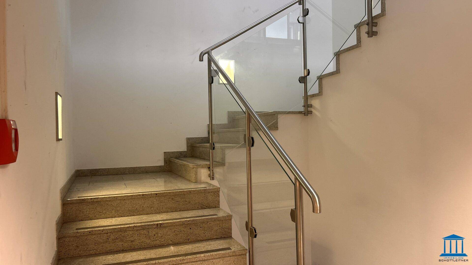 Modernes Treppenhaus mit Granitstufen und elegantem Glas-Edelstahl-Geländer.