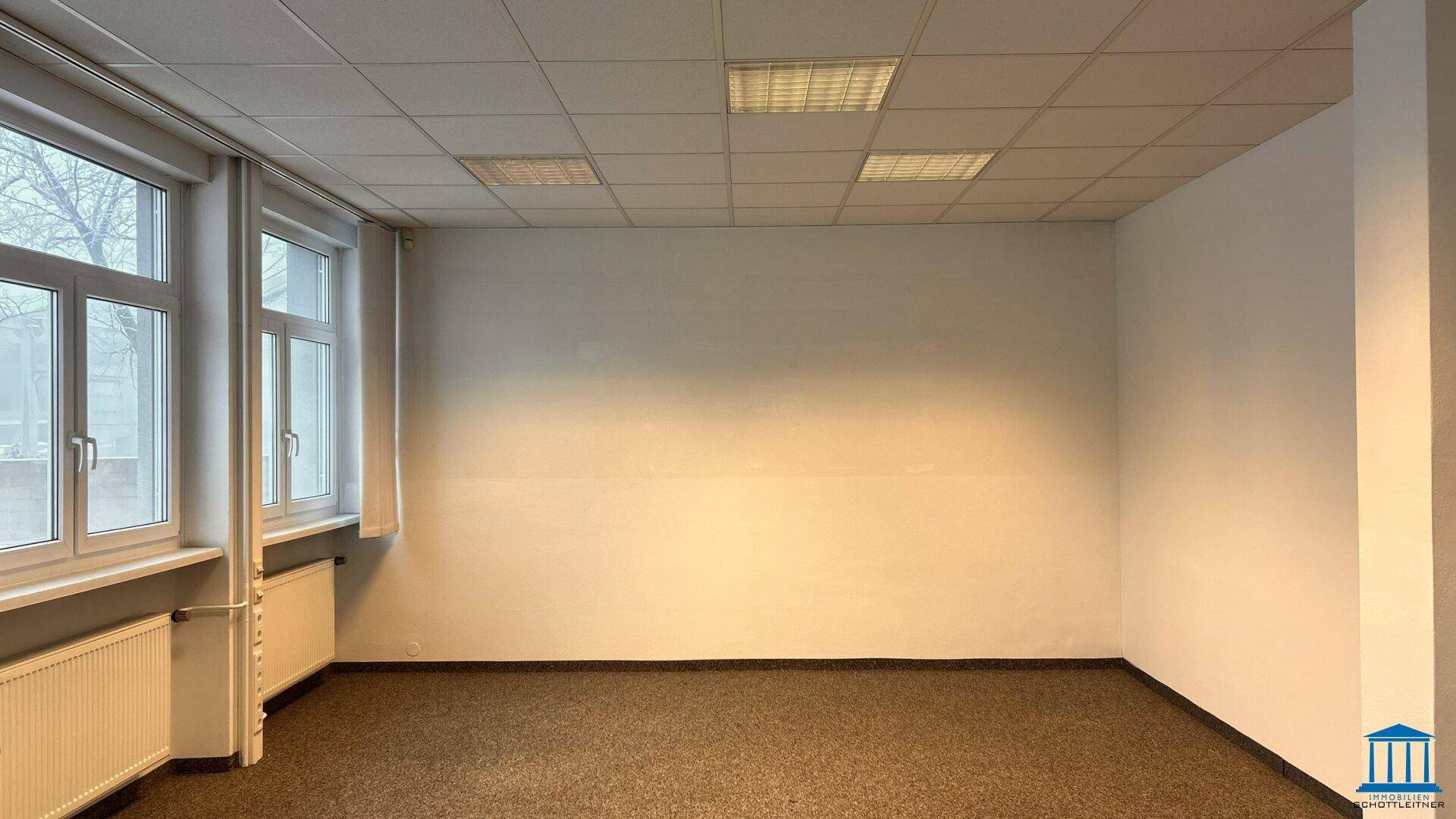 Geräumiges Büro mit Teppichboden, Fenstern und viel Tageslicht.