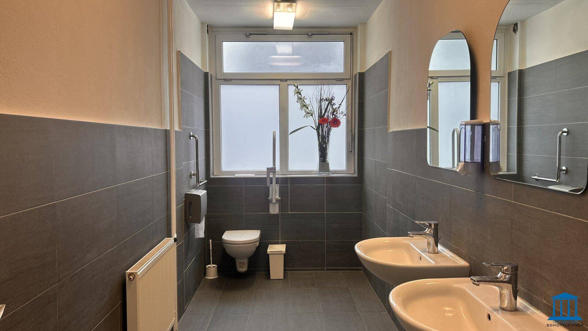 Geräumiges Badezimmer mit zwei Waschbecken, Toilette und Fenster.