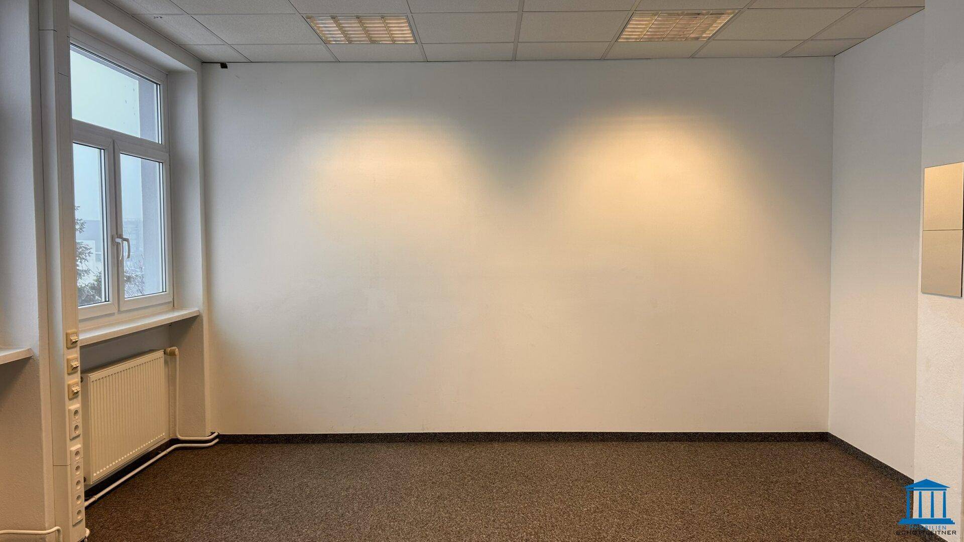Geräumiges Büro mit Teppichboden, Fenstern und viel Tageslicht.