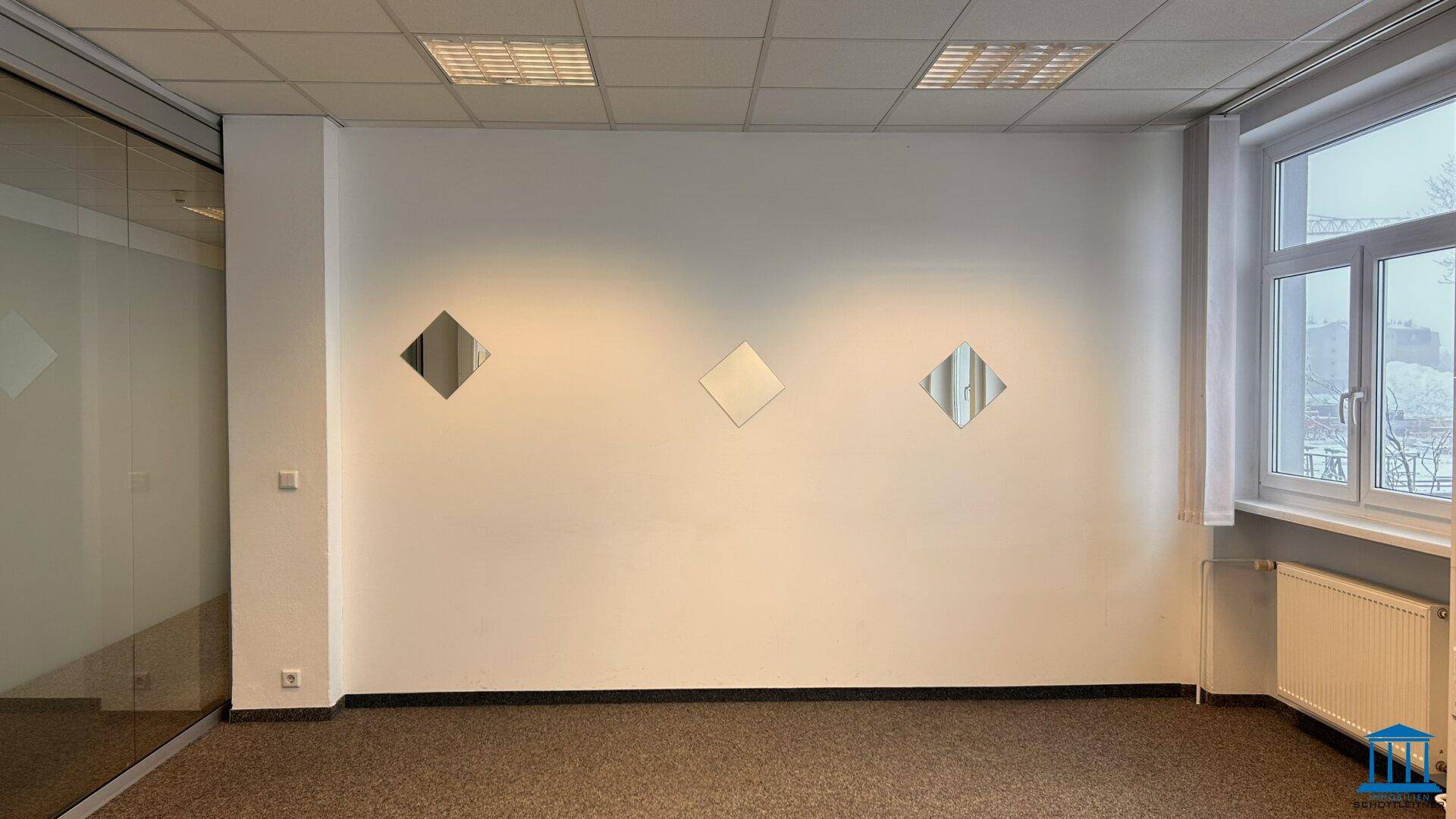 Büro mit Teppichboden, weißen Wänden und dekorativen Spiegelelementen, bietet vielseitige Nutzungsmöglichkeiten.