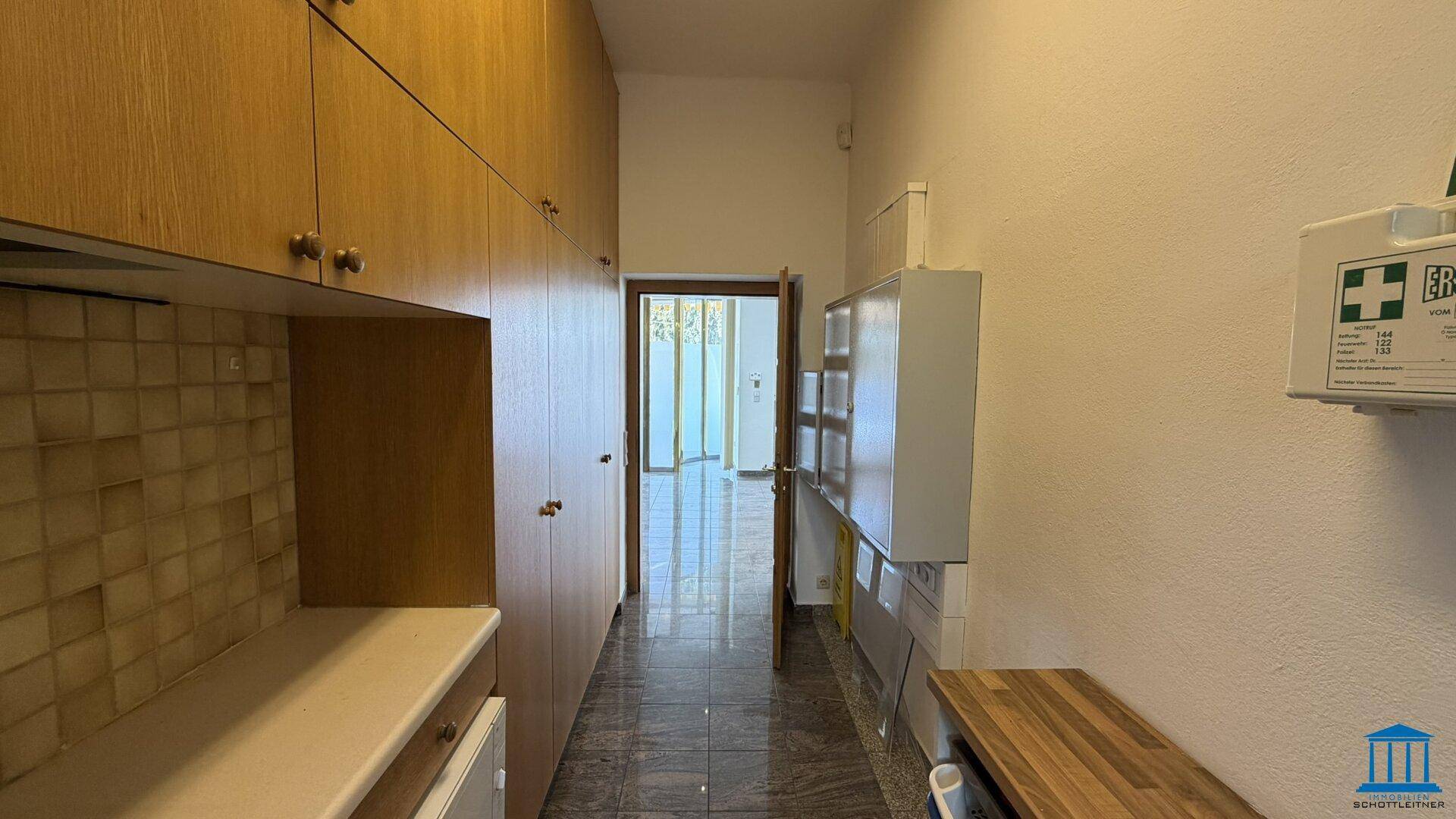 Langer Flur mit Einbauschränken, einer Küchenzeile und einer Tür, die zu einem weiteren Raum führt.