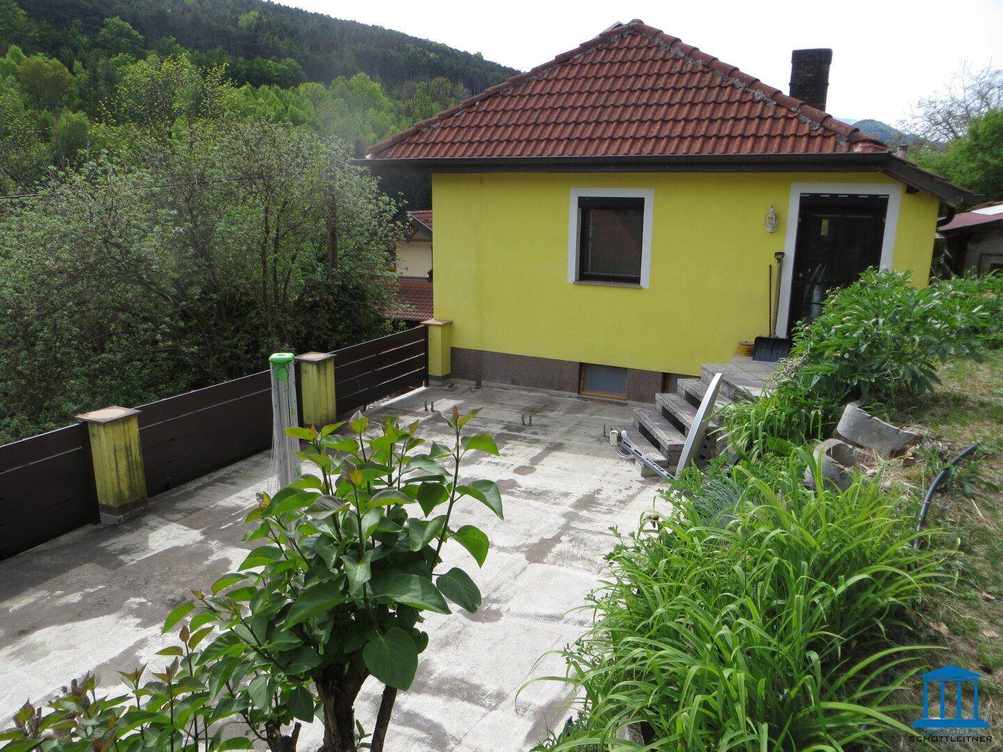Rückansicht des Hauses mit gepflastertem Bereich und Zugang zum Garten.