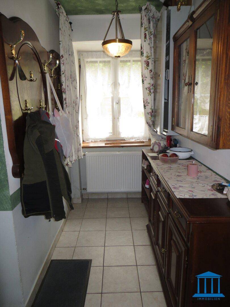 Heller Flur mit Fenster, Heizkörper, Garderobe und traditionellen Holzmöbeln.