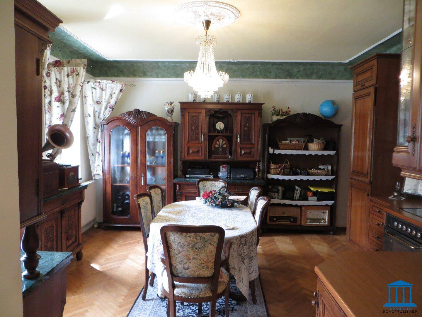 Eleganter Essbereich mit Holztisch, Stühlen, Vitrinen und Kronleuchter.