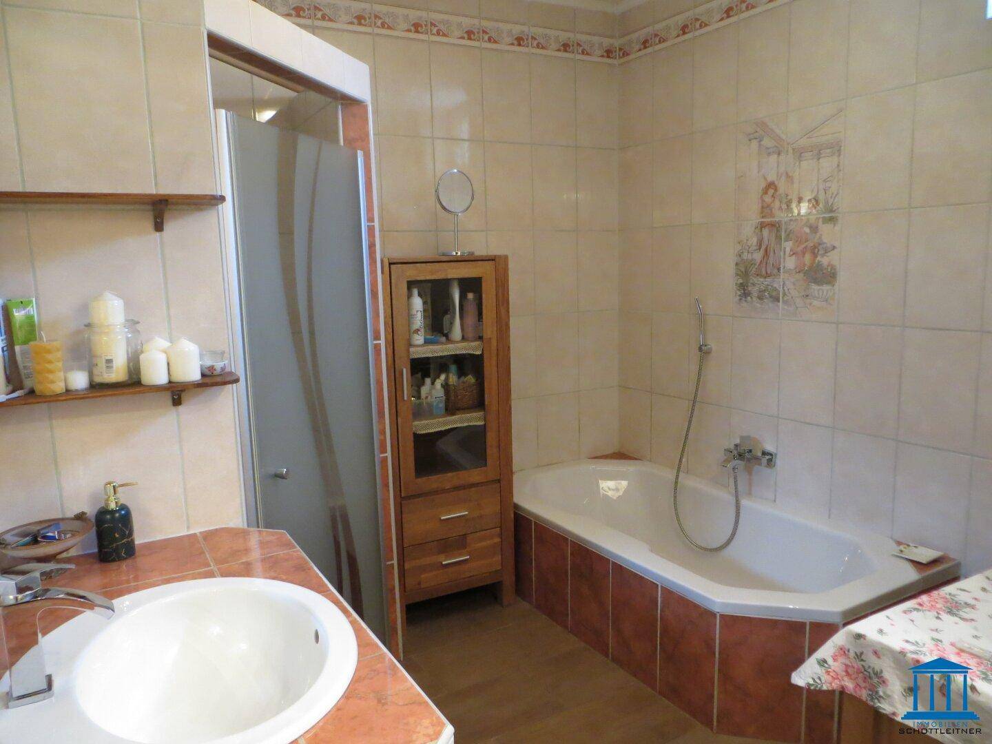Badezimmer mit Eckbadewanne, Duschbereich, Fliesen und Einzelwaschbecken.