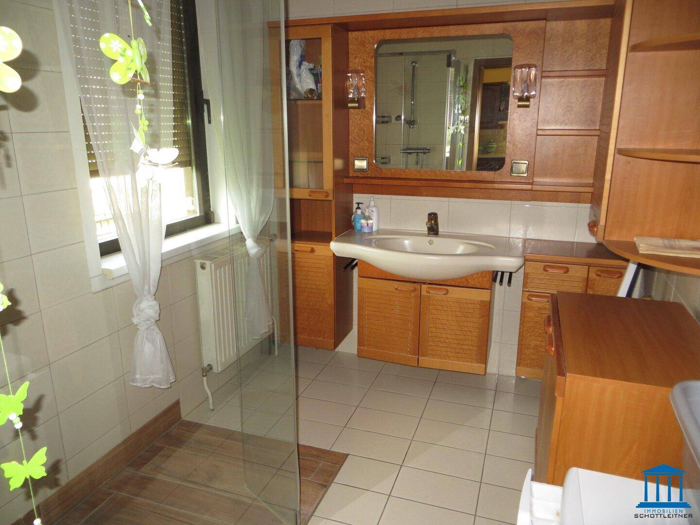 Badezimmer mit Fliesenboden, Einzelwaschbecken und Duschkabine.