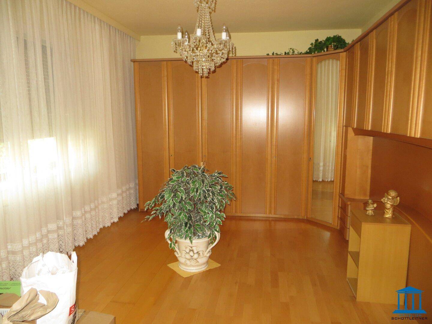 Schlafzimmer mit Parkettboden, großen Einbauschränken und Kronleuchter.