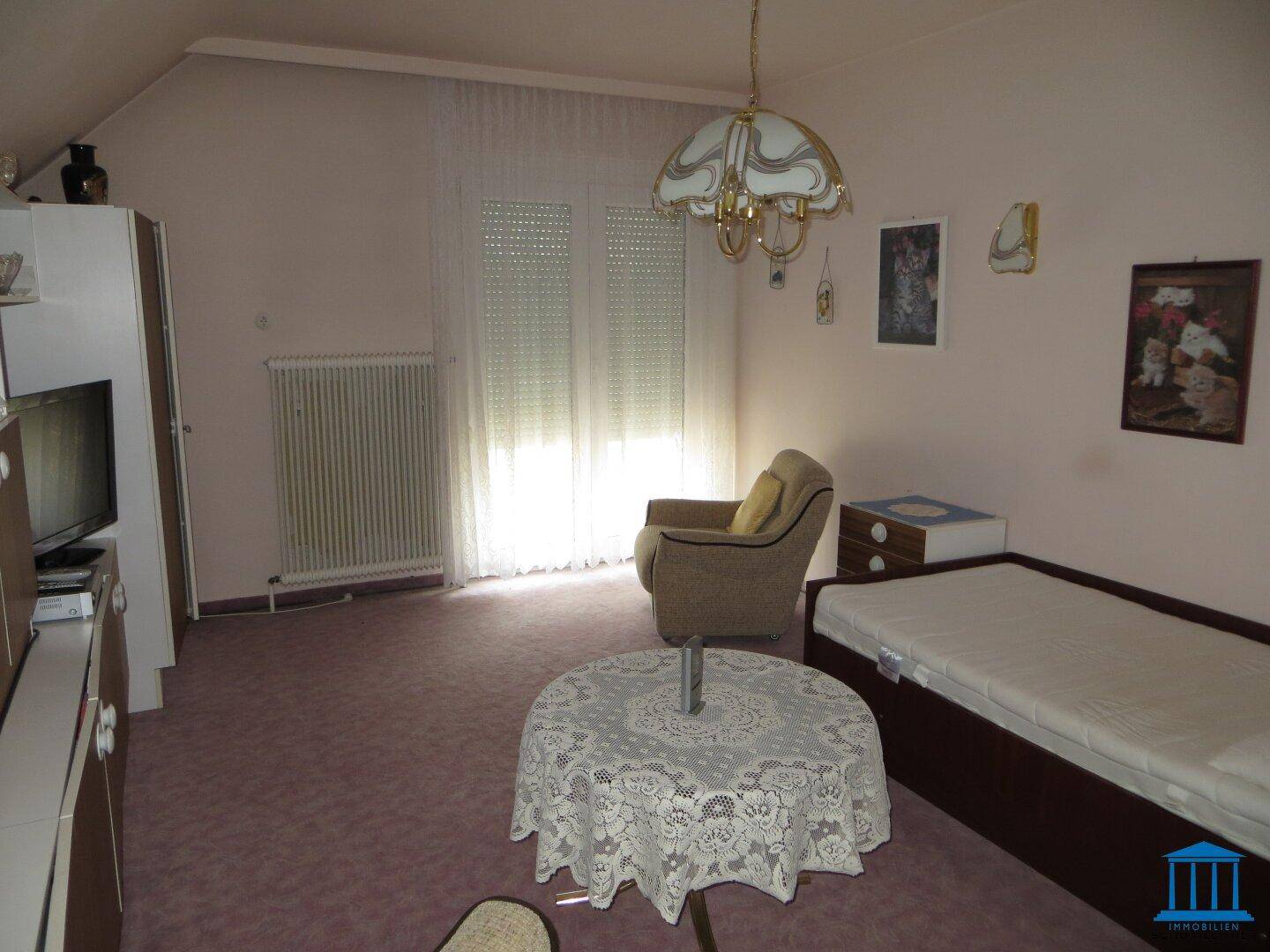 Schlafzimmer im Dachgeschoss mit Teppichboden und Dachschräge.