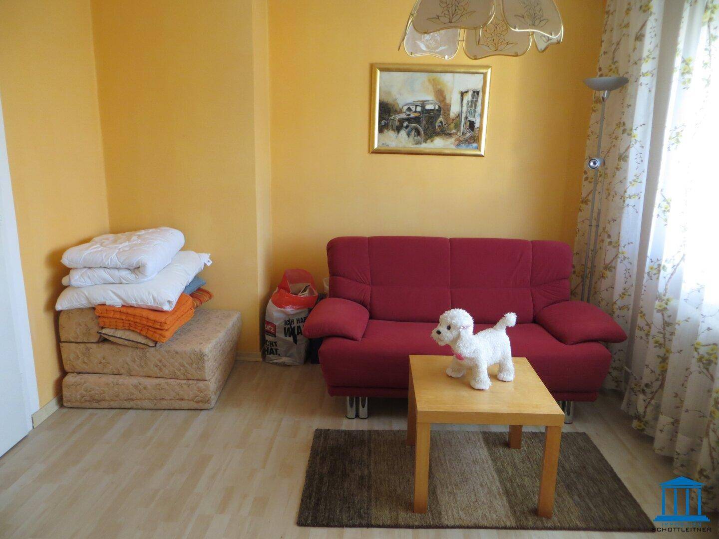 Gemütliches Wohnzimmer mit rotem Sofa, Holztisch und Teppich.