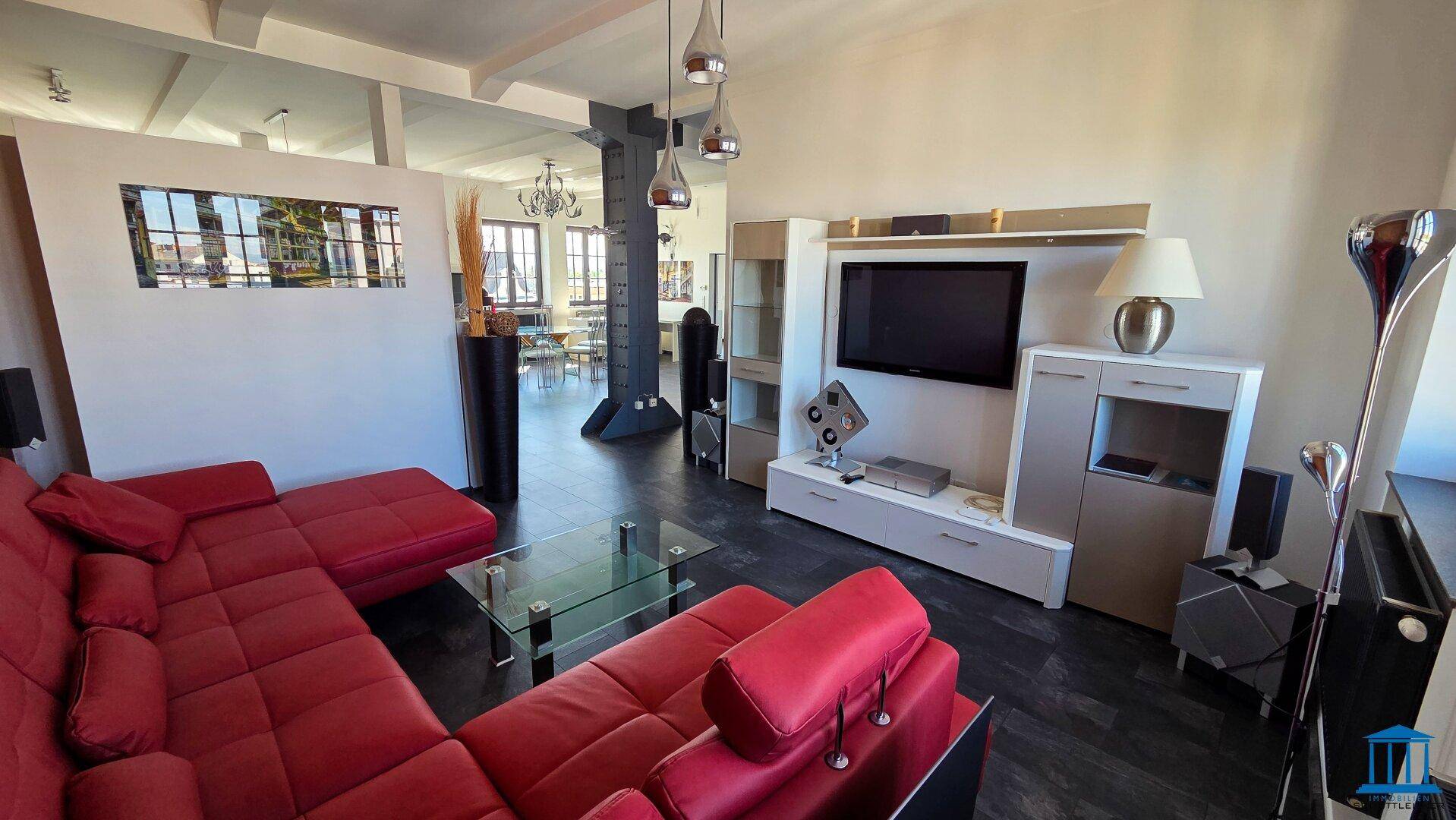Gemütliches Wohnzimmer mit rotem Ecksofa, modernem Mediamöbel und dunklem Boden.