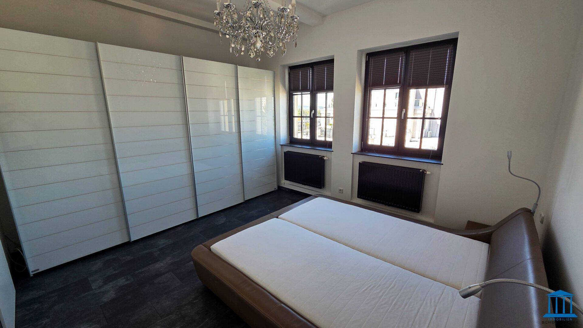 Schlafzimmer mit großem Bett, weißen Einbauschränken und dunklem Boden.