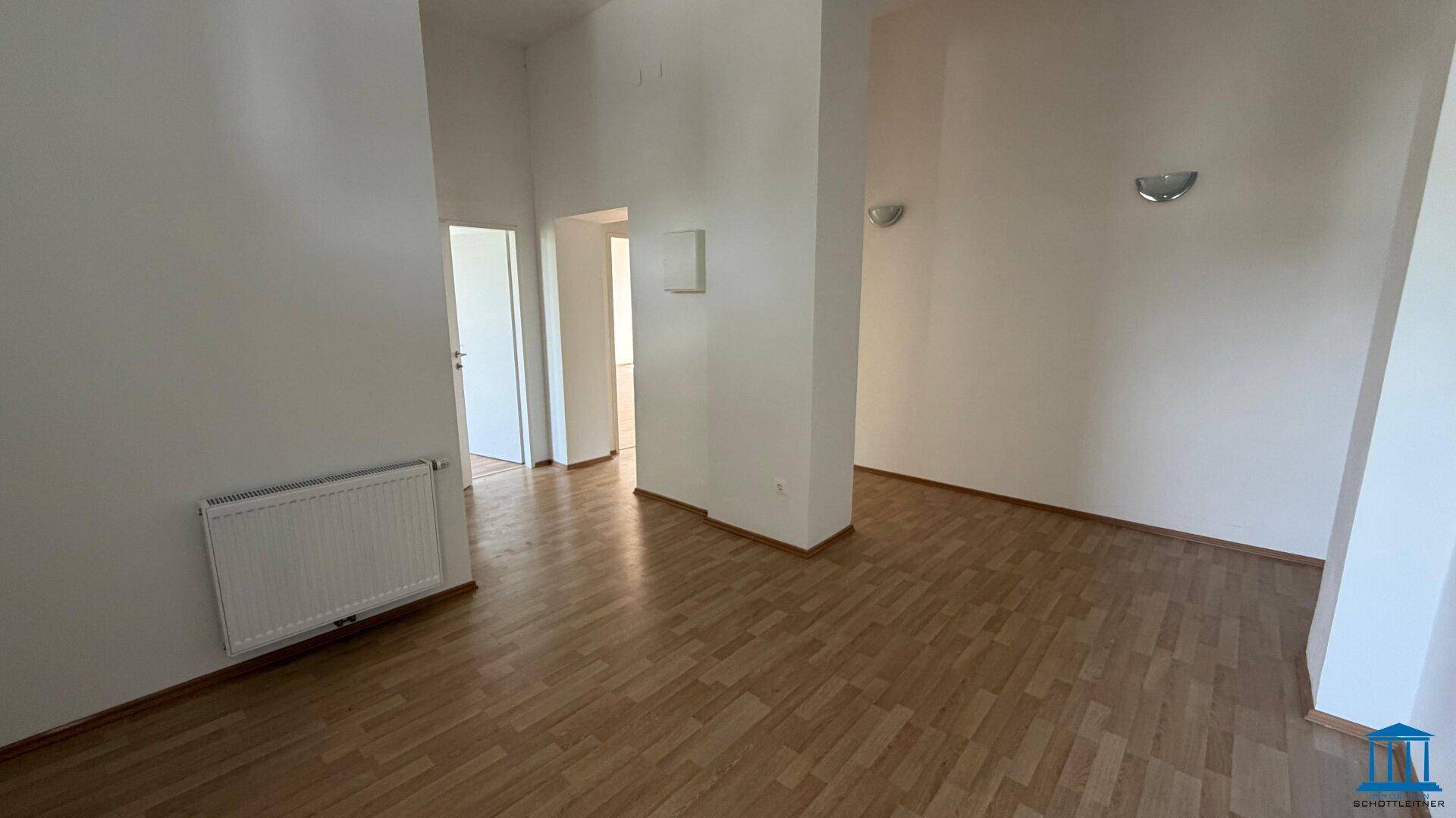 Heller Flurbereich mit Laminatboden, weißen Wänden und Zugang zu mehreren Zimmern.