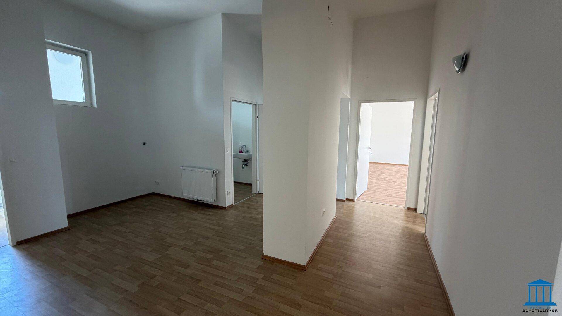 Geräumiger Flur mit Laminatboden, einem kleinen Fenster und Zugang zu verschiedenen Räumen.