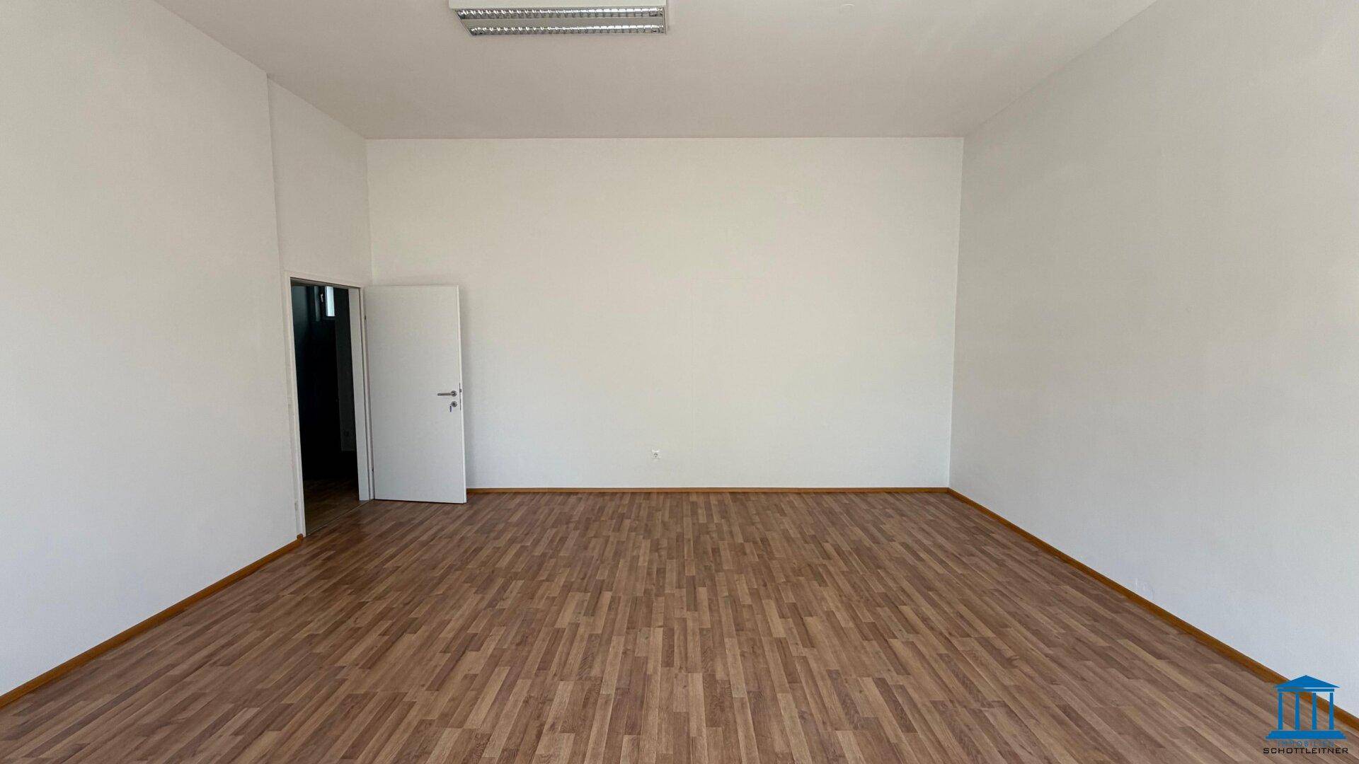 Leerer Raum mit hellem Laminatboden und weiß gestrichenen Wänden, bietet vielseitige Einrichtungsmöglichkeiten.