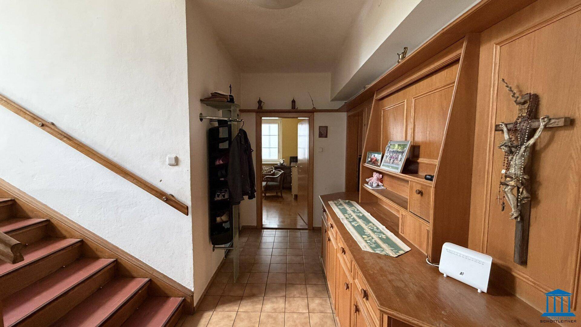 Geräumiger Eingangsbereich mit Holzvertäfelung, Fliesenboden und Treppenaufgang zum Obergeschoss.
