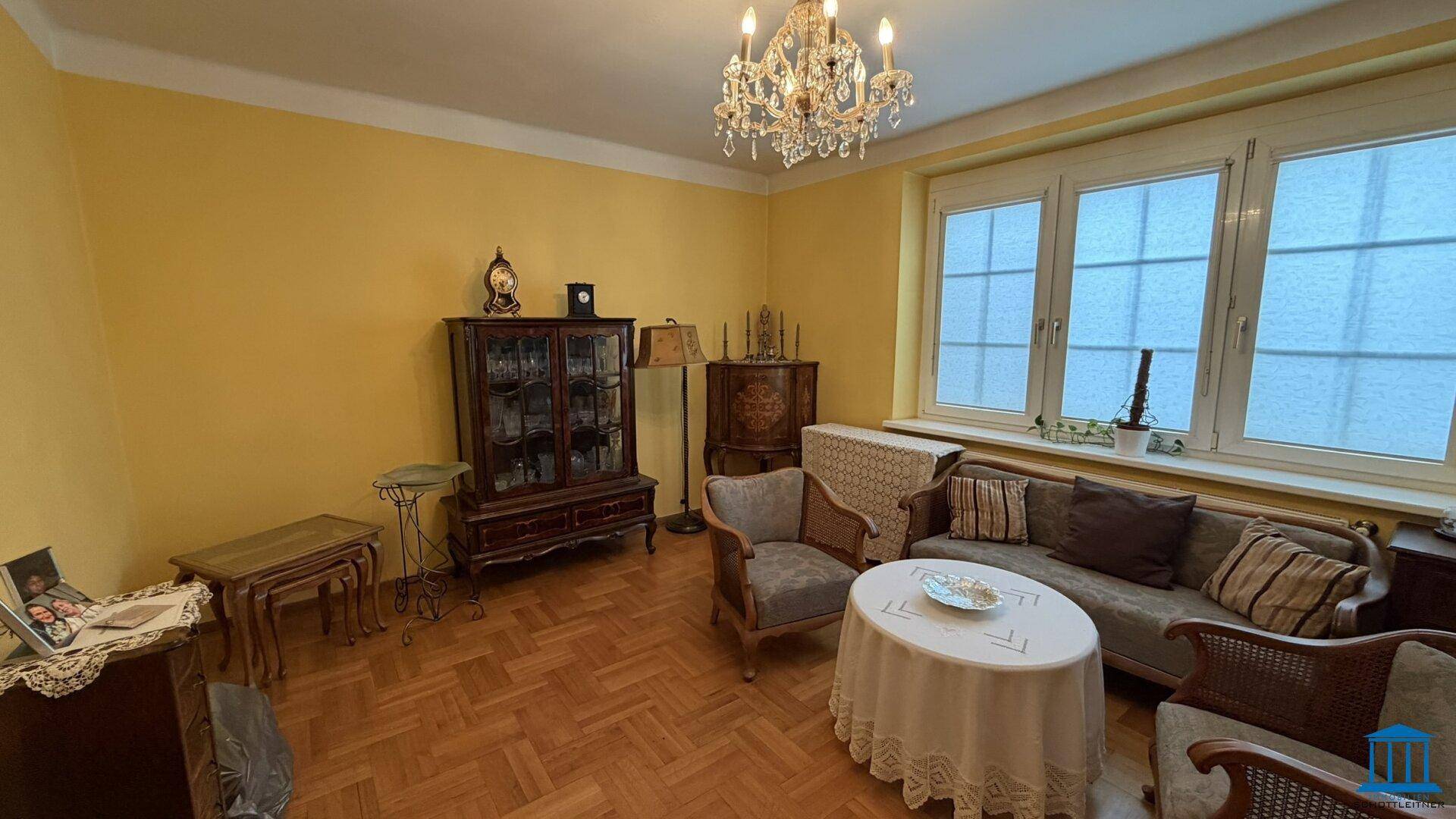 Klassisch eingerichtetes Wohnzimmer mit Parkettboden, Kronleuchter und antiken Möbeln.