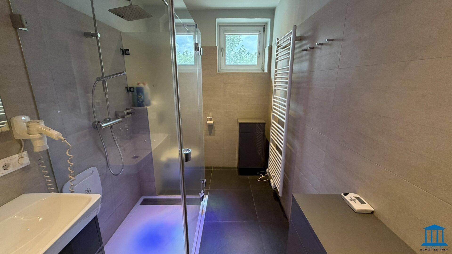 Modernes Badezimmer mit ebenerdiger Dusche, Handtuchheizkörper und Fenster.