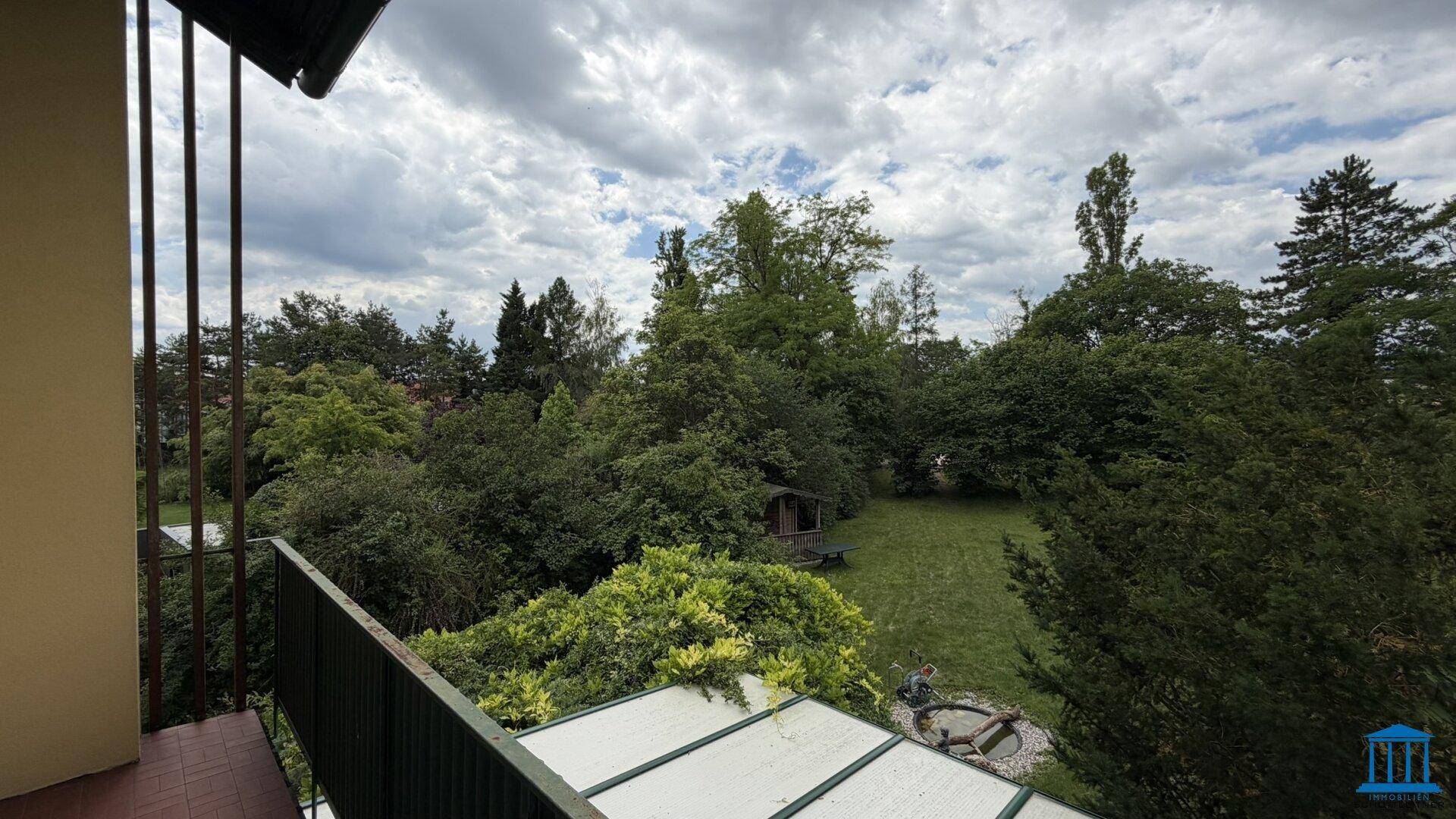 Balkon mit weitem Blick über den grünen Garten und die umliegende Landschaft.