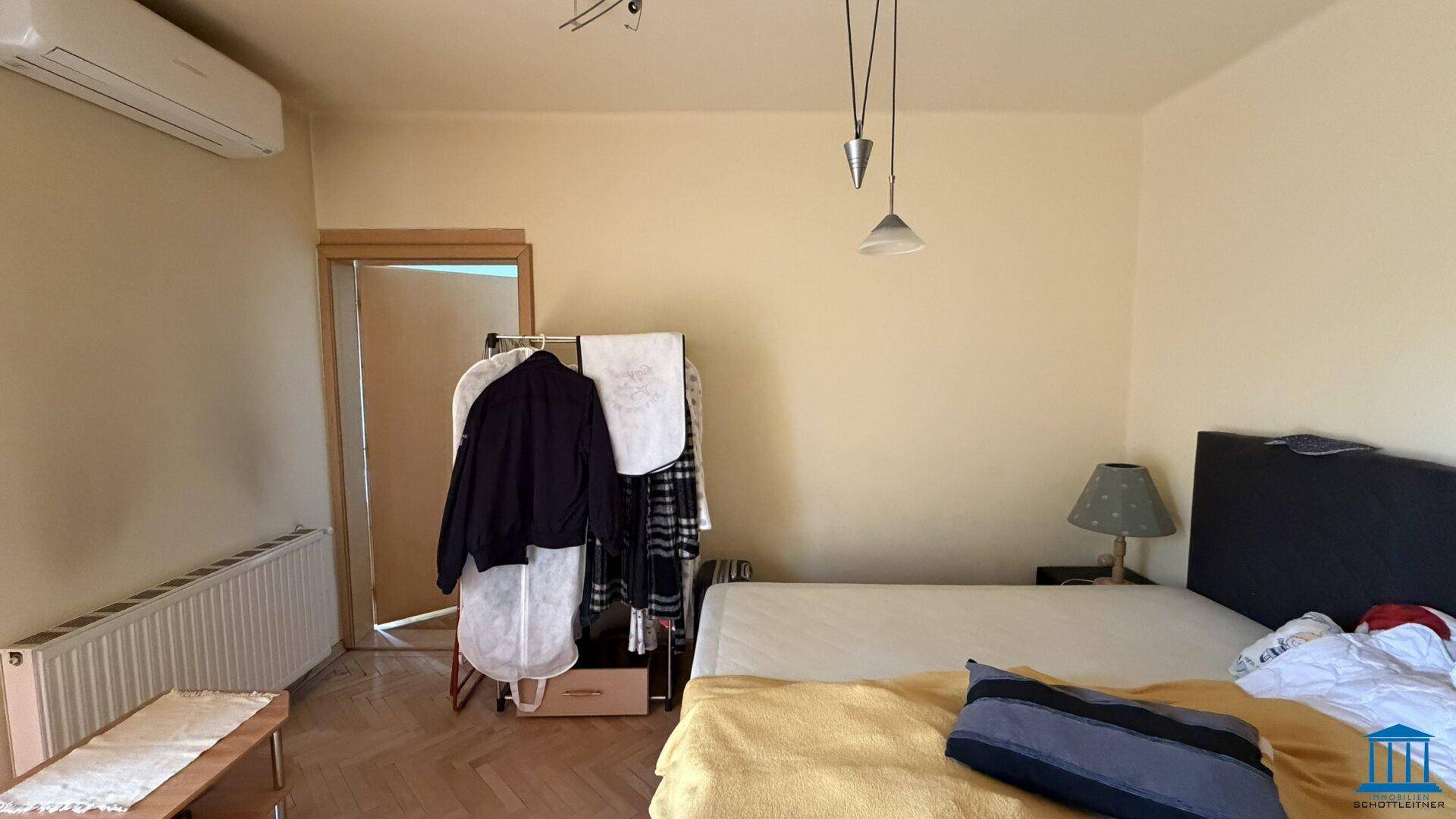 Schlafzimmer mit Doppelbett, Klimaanlage und Kleiderständer, heller Raum, sorgt für angenehmes Raumklima.