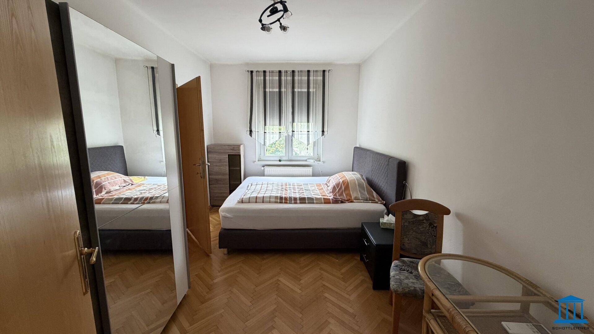 Schlafzimmer mit zwei Einzelbetten und Holzboden, Fenster mit gestreiften Vorhängen, bietet eine ruhige Schlafumgebung.