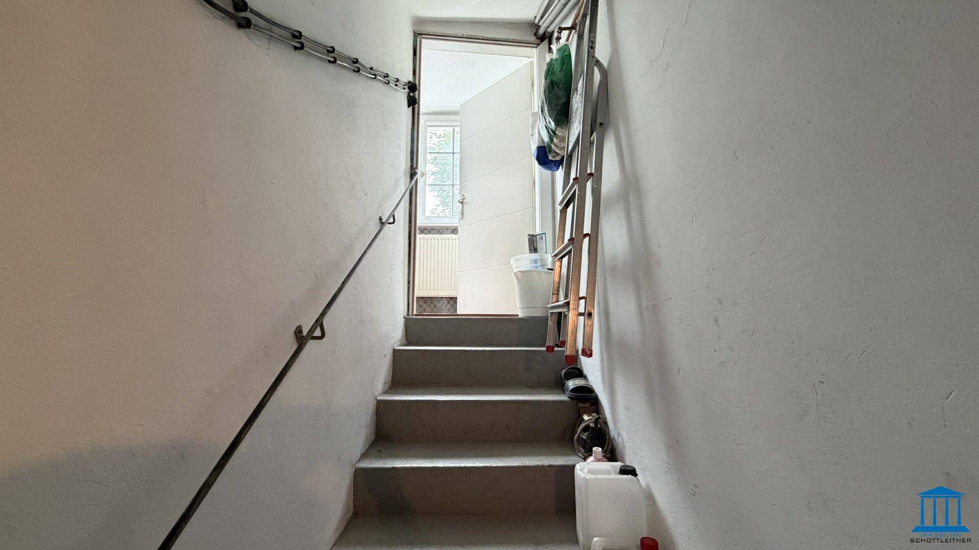 Betontreppe mit Handlauf führt nach oben, möglicherweise aus einem Kellerbereich.