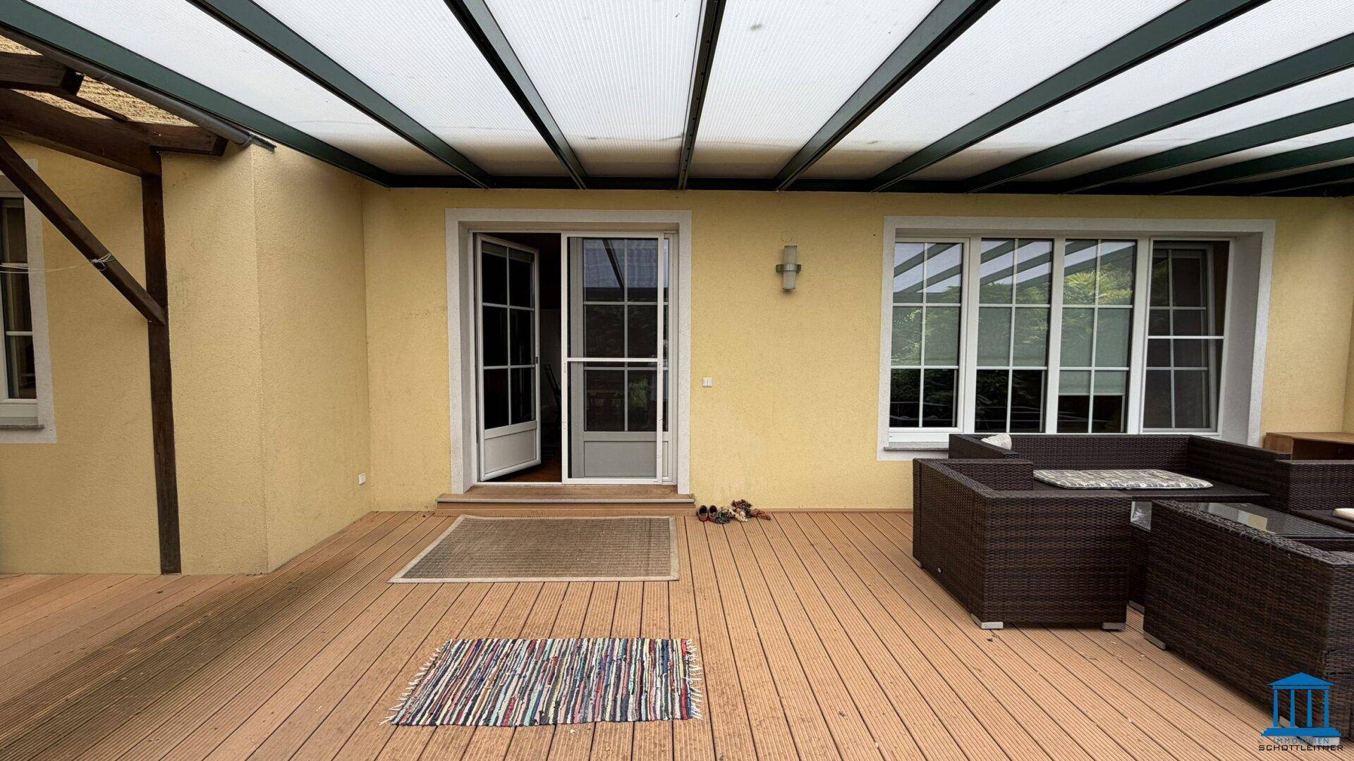 Überdachte Terrasse mit Holzboden und Loungemöbeln, ideal für entspannte Stunden im Freien.