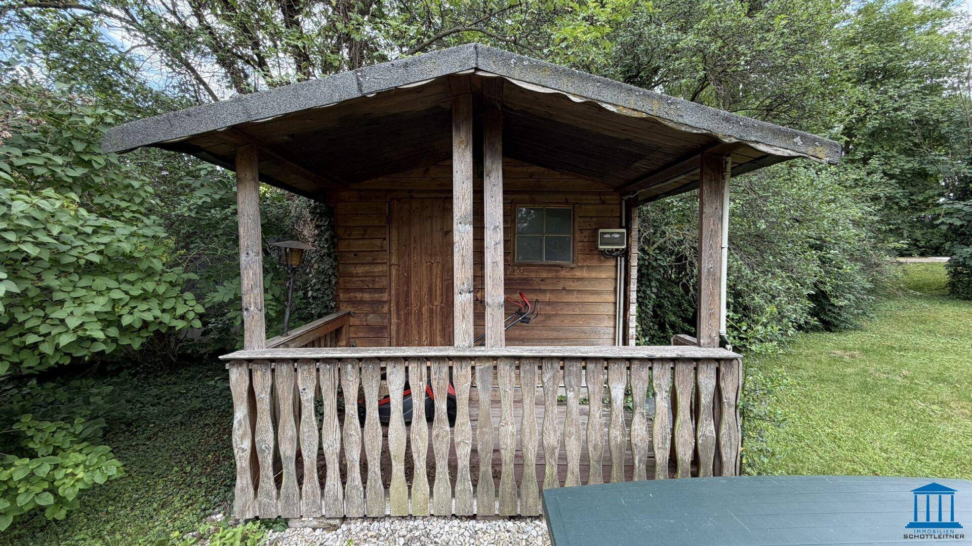 Detailansicht eines Holzschuppens oder Gartenhauses mit kleiner Veranda im Grünen.