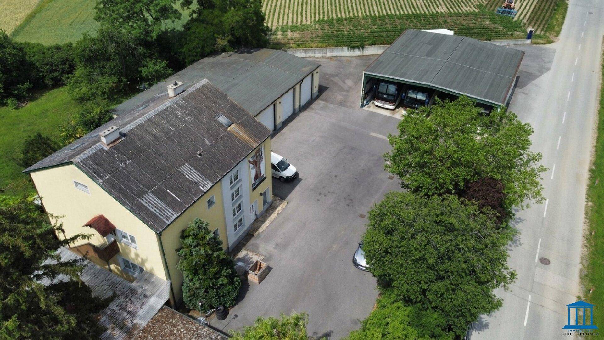 Luftaufnahme des Anwesens mit Wohnhaus, Garagen und einer weiteren Halle, umgeben von Feldern.