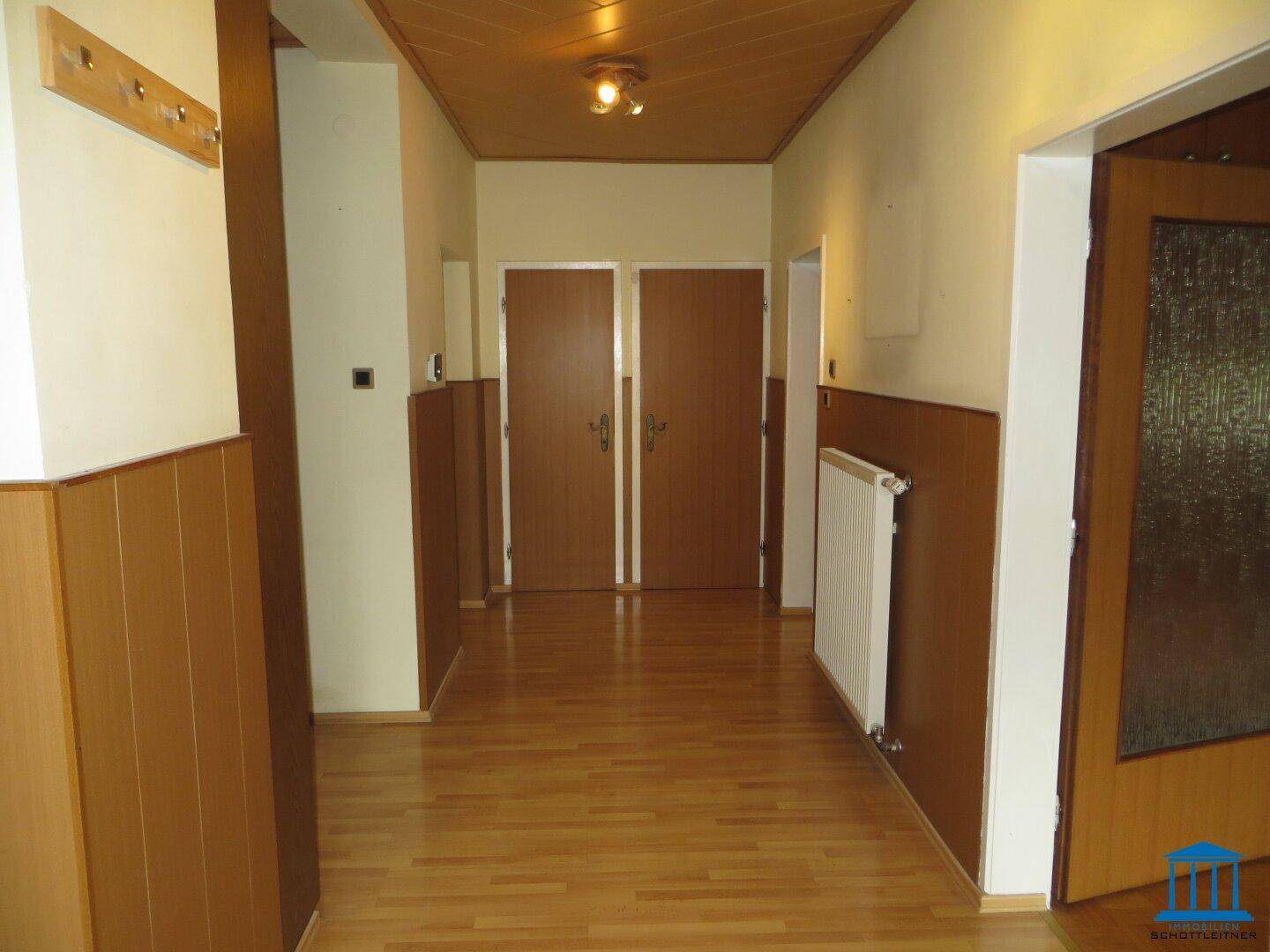 Flur mit Holzvertäfelung an Wänden und Decke, Holztüren und Parkettboden, im traditionellen Stil.