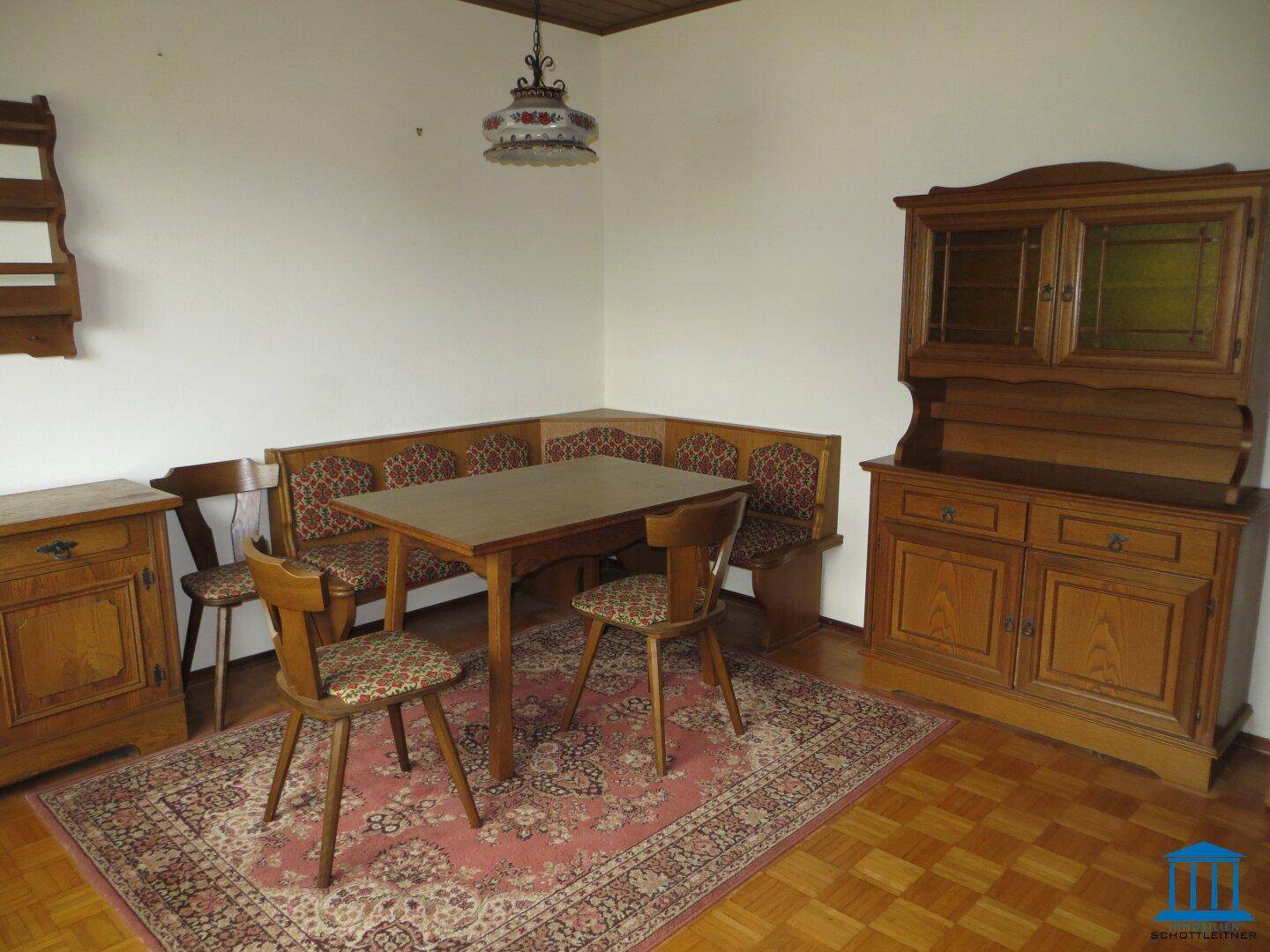 Gemütlicher Essbereich mit traditionellen Holzmöbeln, Eckbank, Esstisch und einem gemusterten Teppich.