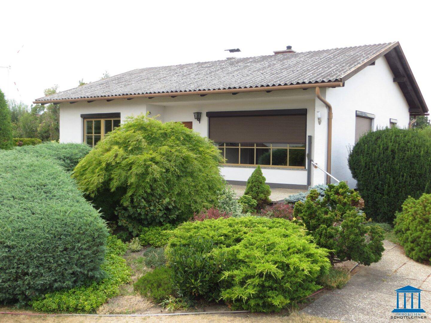 Das Einfamilienhaus präsentiert sich mit einem üppigen, grünen Vorgarten und einem Kiesweg.