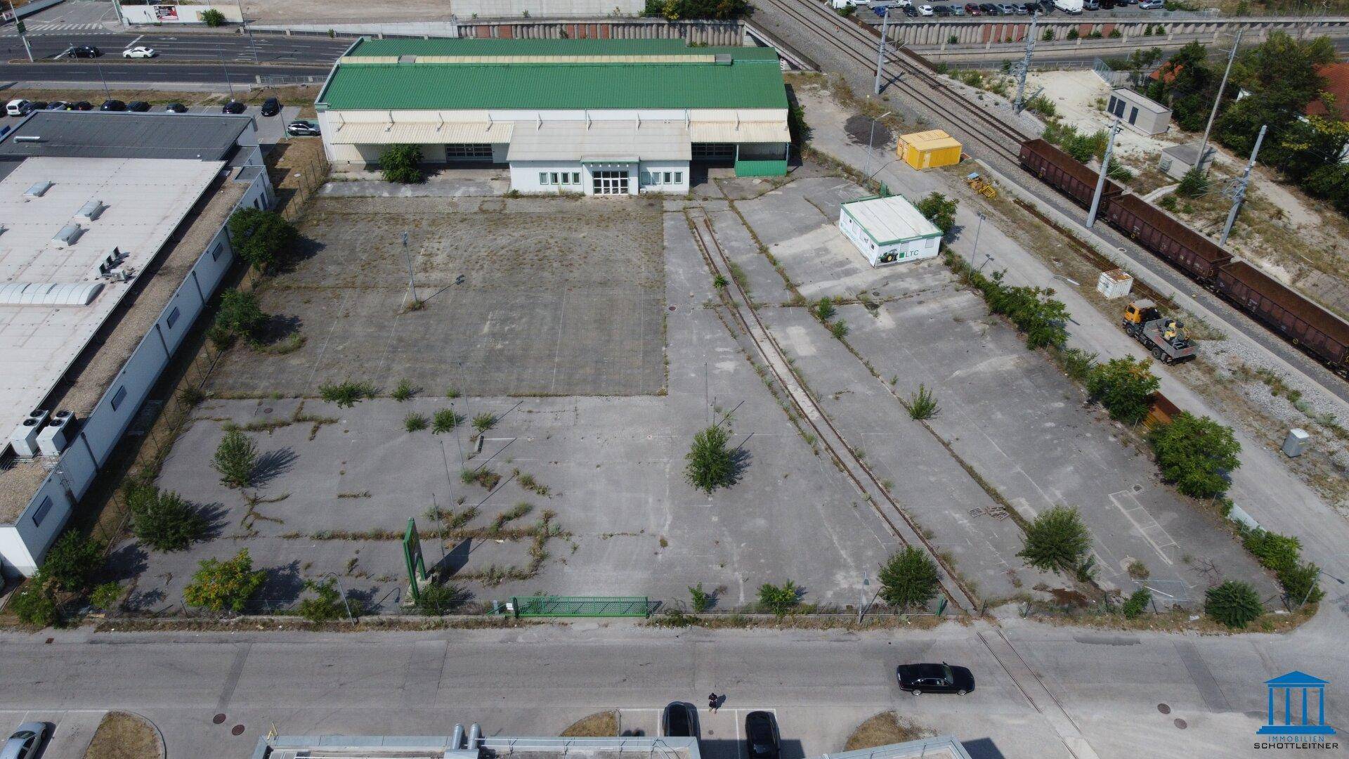 Vogelperspektive des Gewerbeareals mit angrenzenden Bahngleisen und weitläufigen befestigten Flächen.