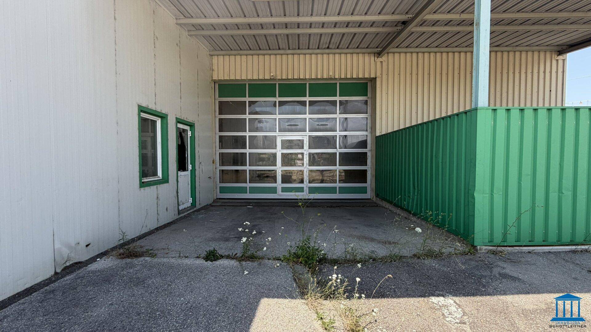 Nahaufnahme eines großen, verglasten Garagentors mit grünen Akzenten und Zufahrtsbereich.
