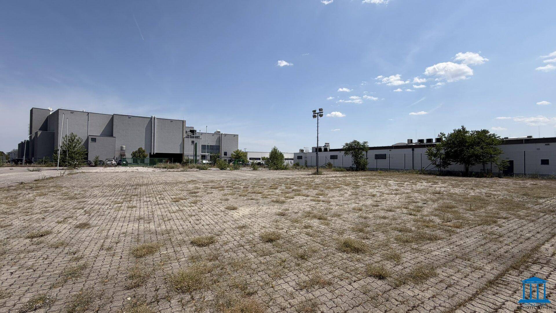 Weitläufige, gepflasterte Freifläche mit Blick auf weitere Industriegebäude in der Ferne.