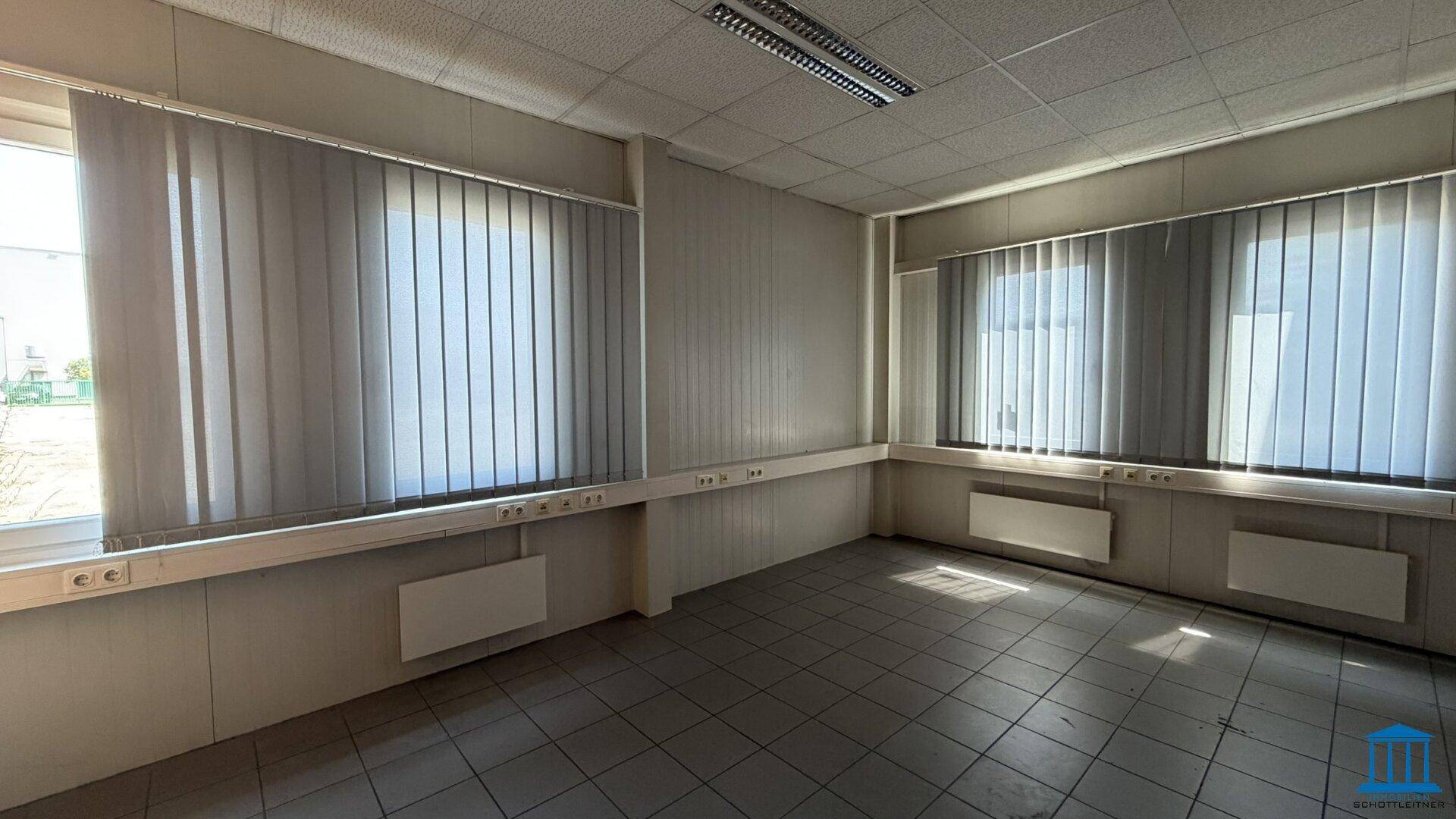 Helles Büro mit Fliesenboden und mehreren Fenstern, die viel Tageslicht hereinlassen.
