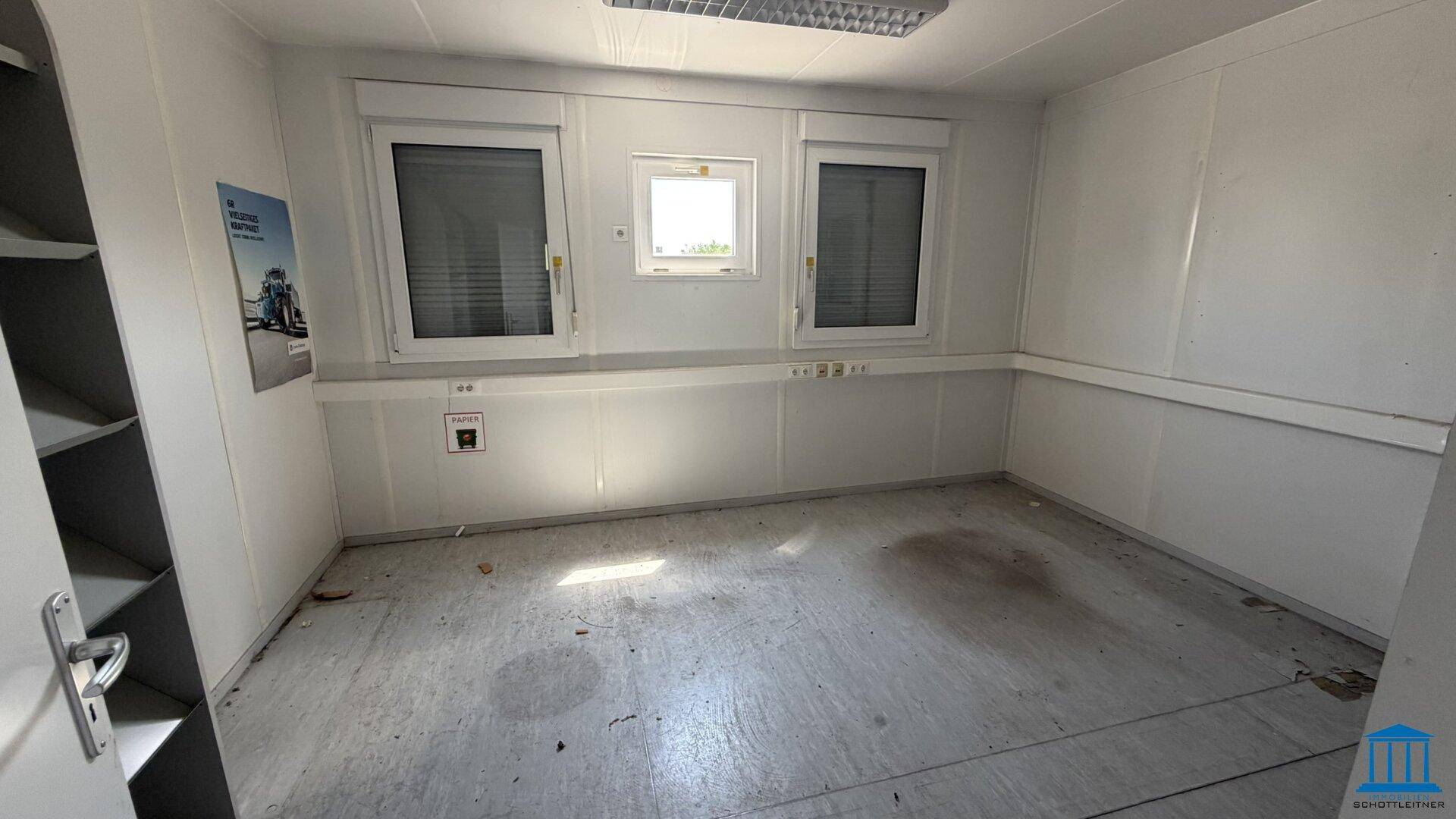 Büroraum in einem Container mit Vinylboden, Fenstern mit Rollläden und offenem Regal.