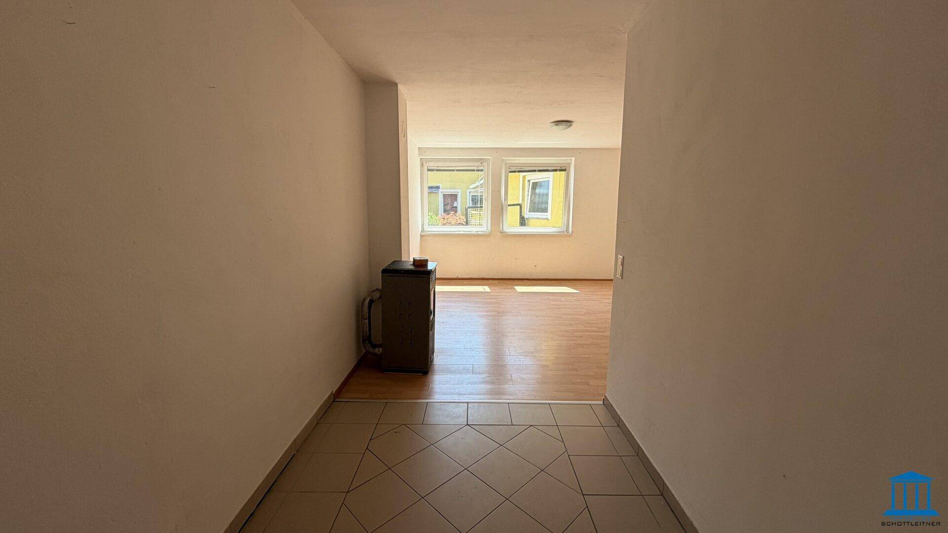 Flur mit Fliesenboden, der in einen hellen Wohnbereich mit Laminatboden übergeht.
