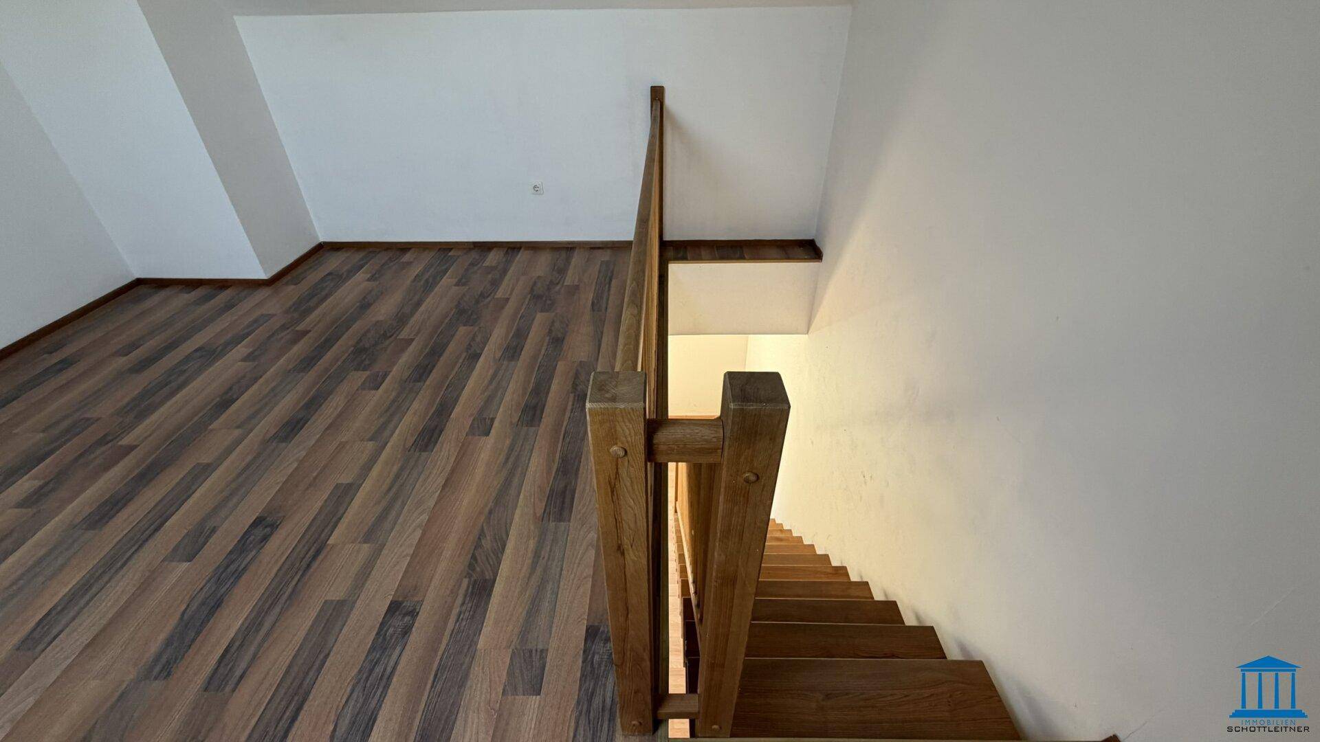 Blick von oben auf die Holztreppe, die das Dachgeschoss mit den unteren Etagen verbindet.