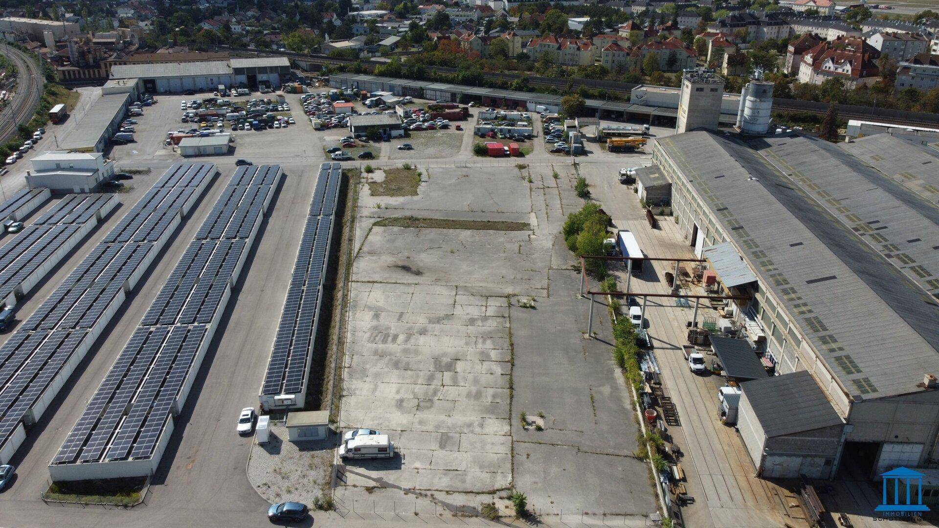 Weitläufige Luftaufnahme eines Gewerbegebiets mit Solaranlagen, Parkplätzen und Industriegebäuden.