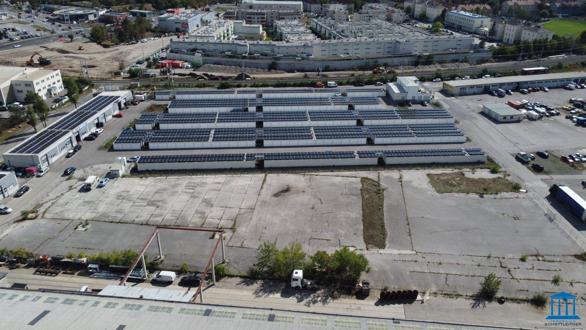 Luftaufnahme mit Fokus auf die ausgedehnten Solaranlagen und den großen befestigten Freibereich.