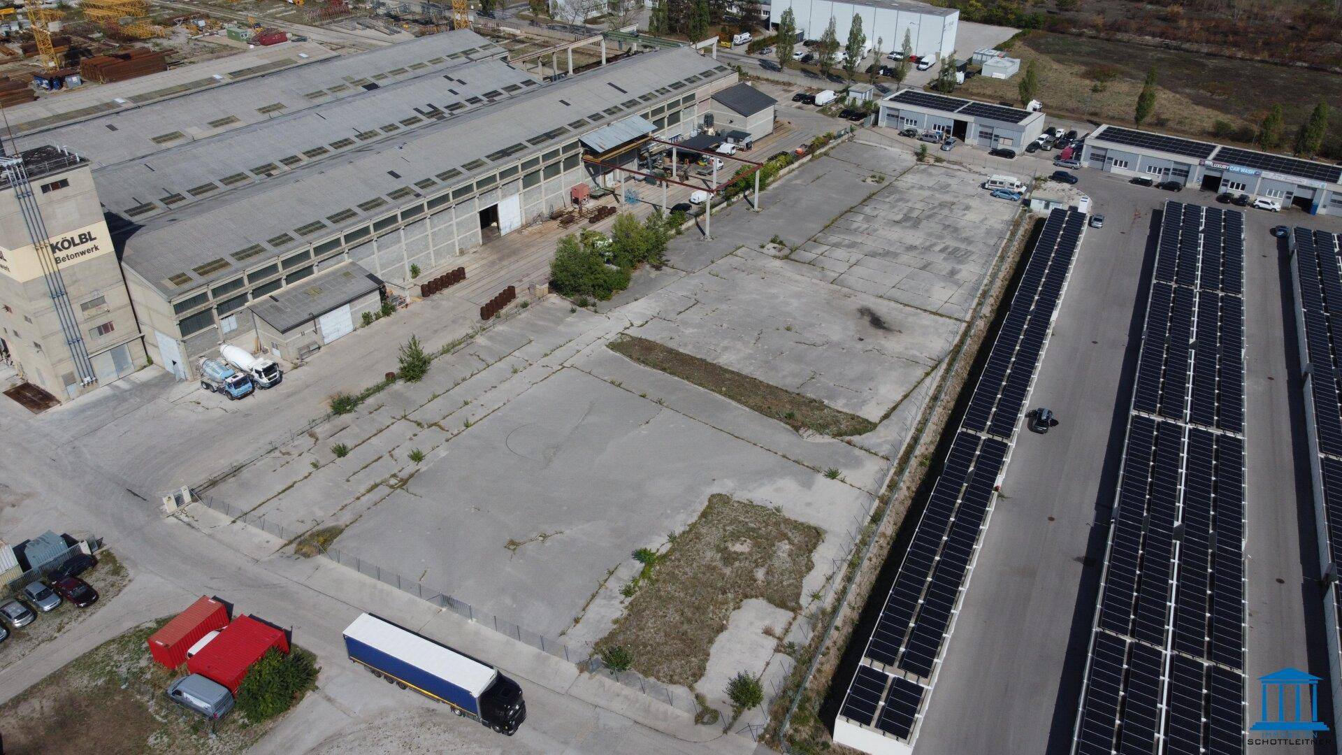 Übersicht aus der Vogelperspektive über das Industrieareal mit Hallen, Freiflächen und Reihen von Solarmodulen.