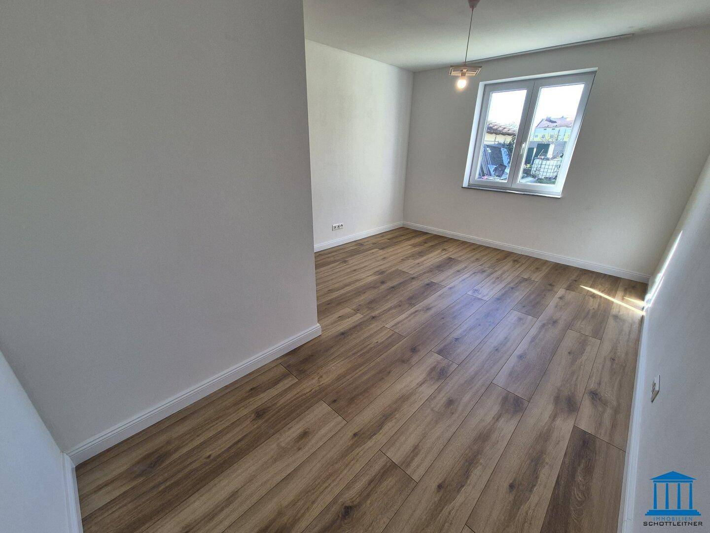 Gemütliches Schlafzimmer mit Laminatboden und einem Fenster, das den Raum erhellt.