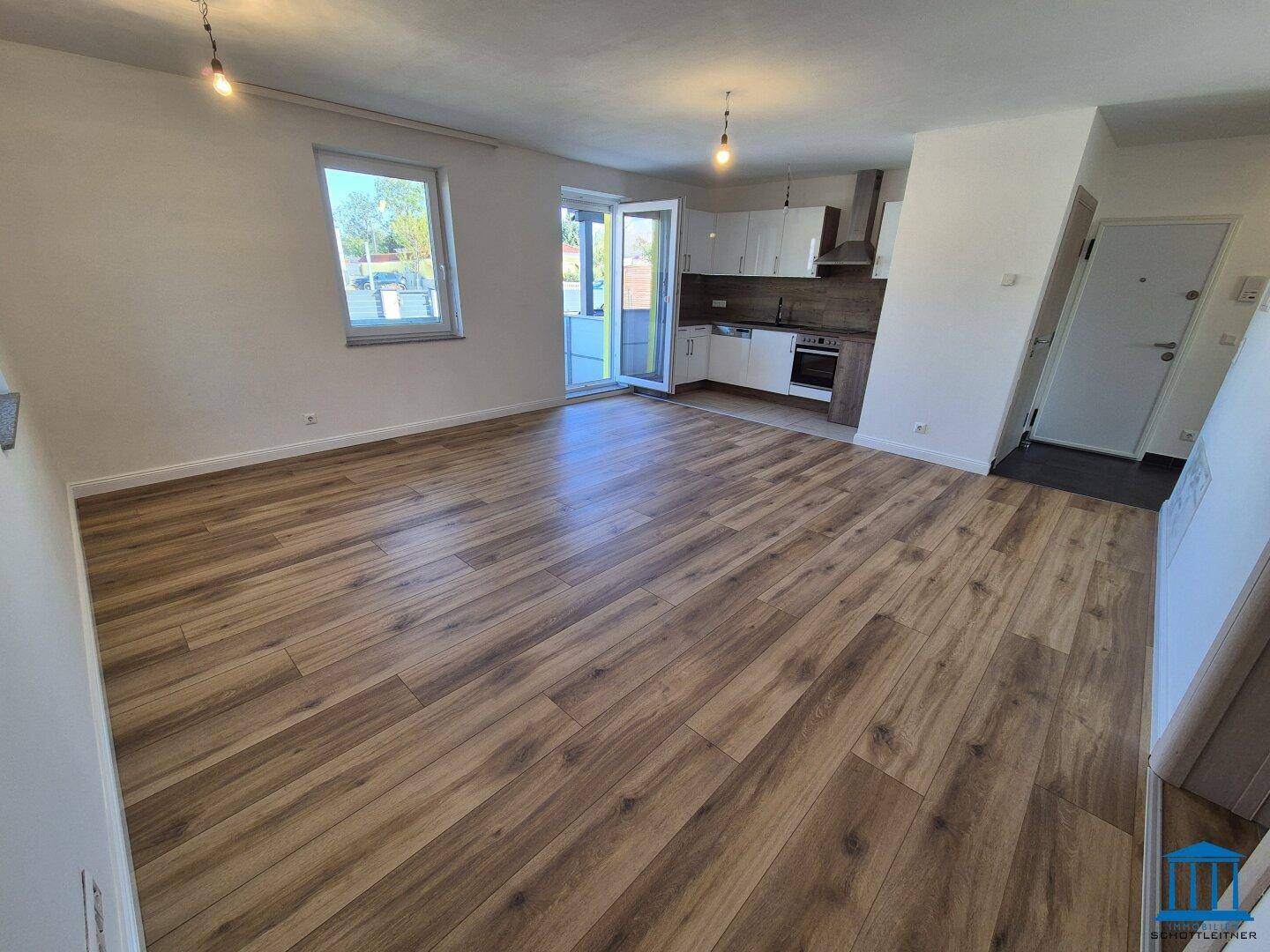 Heller offener Wohnbereich mit modernem Laminatboden und integrierter Küchenzeile.