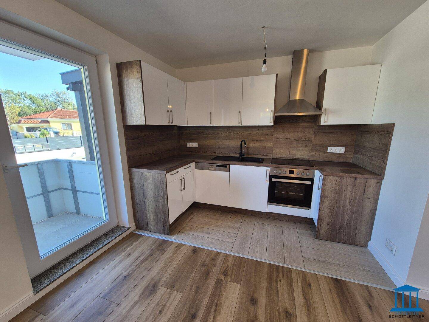 Moderne Einbauküche mit weißen Hochglanzfronten, Holzdekor und Zugang zum Außenbereich.